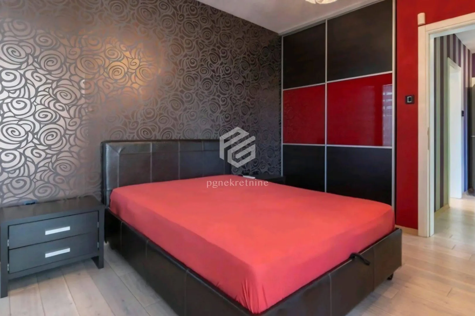 Furnished bedroom with a double bed, bedside table, and fitted wardrobe.
