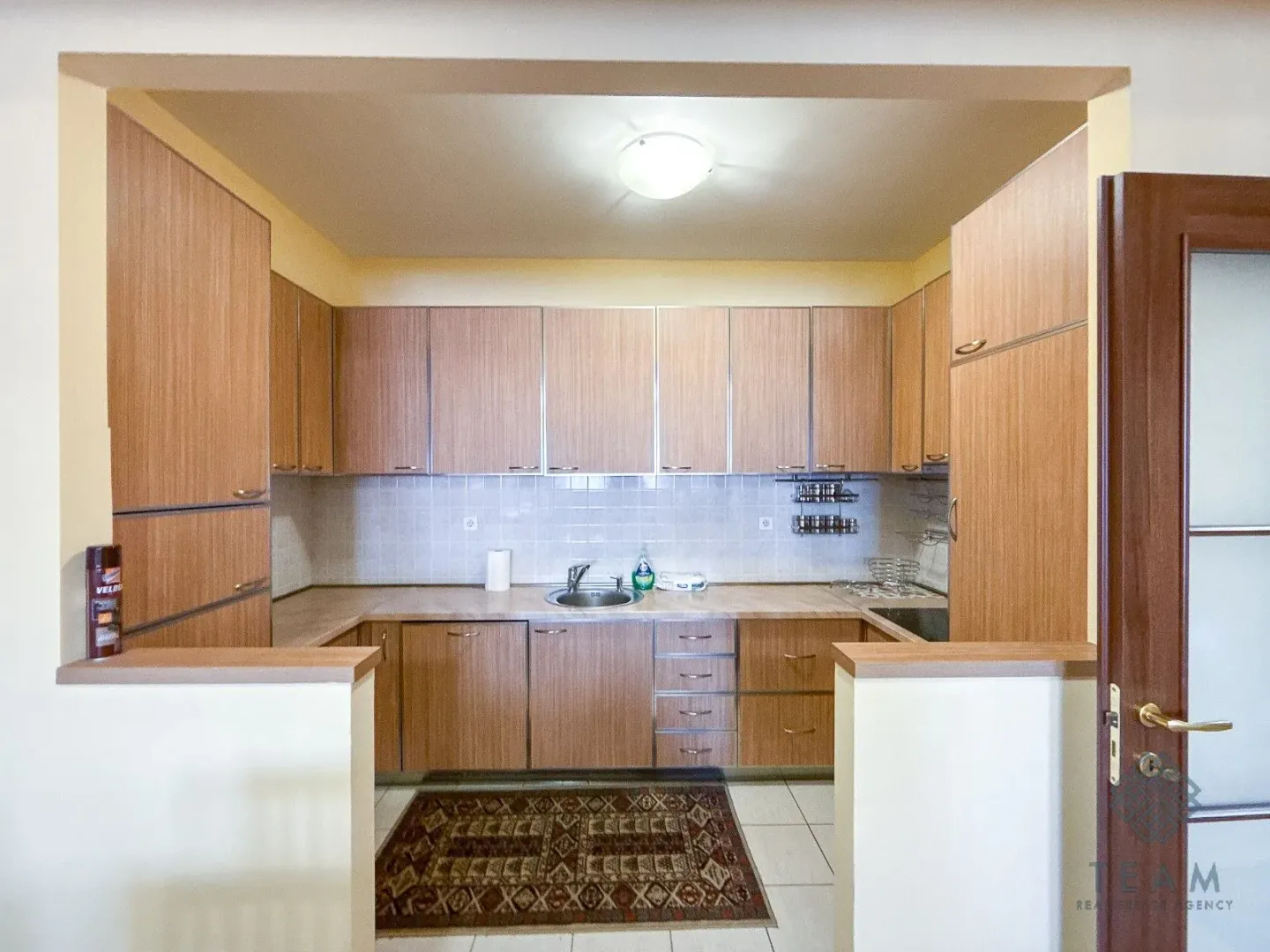 Separate kitchen with wooden cabinetry and a sink.