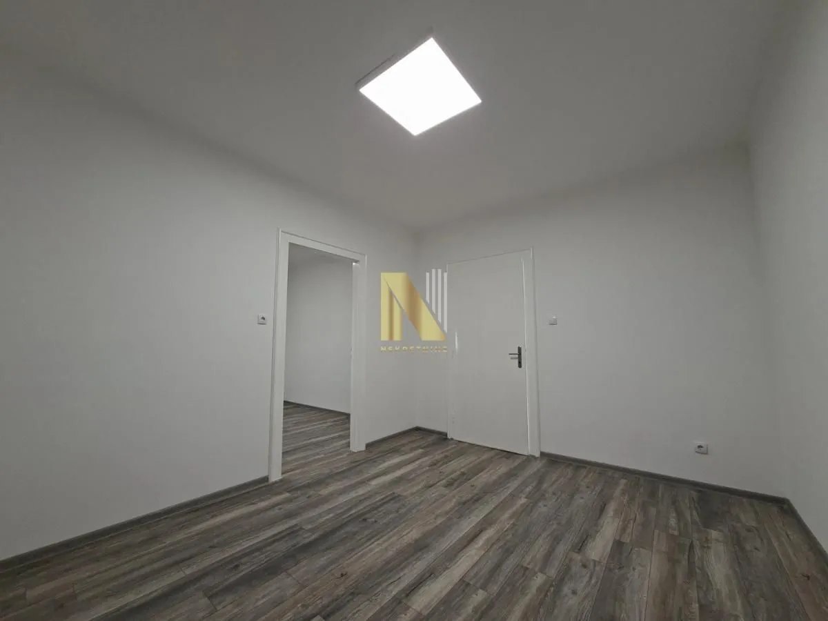 Empty room with laminate flooring and white walls.