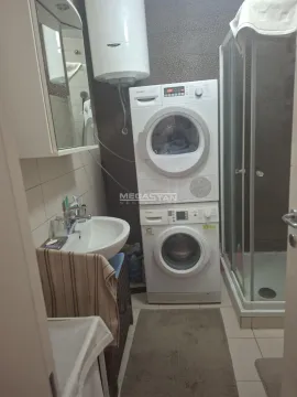 Bathroom with a shower cabin, washbasin, and a stacked washing machine and dryer. - image 5