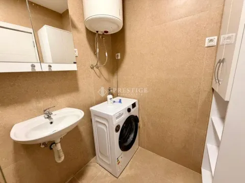 Kupatilo opremljeno umivaonikom, veš mašinom i bijelim elementima. - image 12