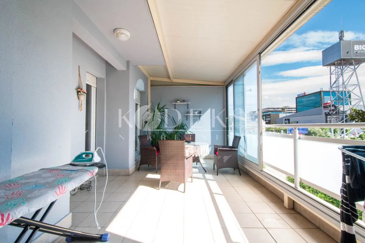 Enclosed balcony with seating furniture and city view.