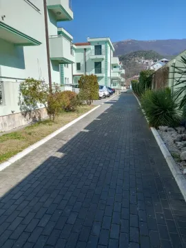 Popločana staza pored stambene zgrade sa uređenim dvorištem. - image 2