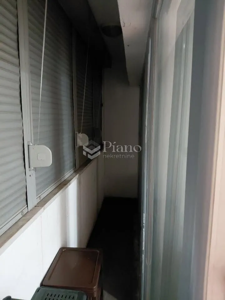 Enclosed balcony with window blinds.