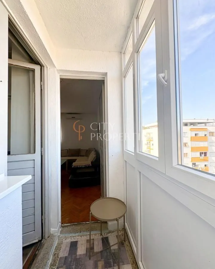 Zastakljeni balkon sa pogledom na okolne zgrade i pogledom u unutrašnjost stana.