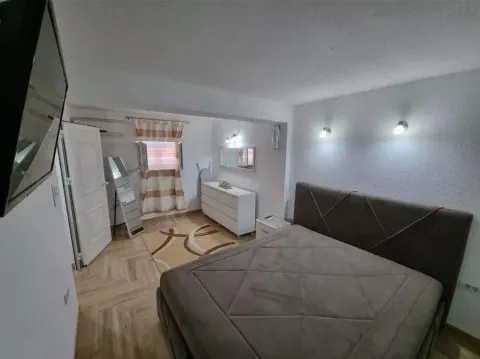 Spavaća soba sa bračnim krevetom, komodom i televizorom na zidu. - image 4