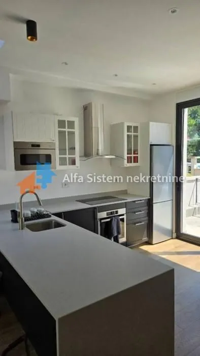 Moderna kuhinja sa ugrađenim aparatima i šankom.