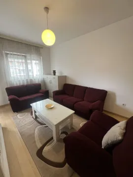 Svijetla dnevna soba sa tamnocrvenom garniturom i bijelim stolom. - image 10