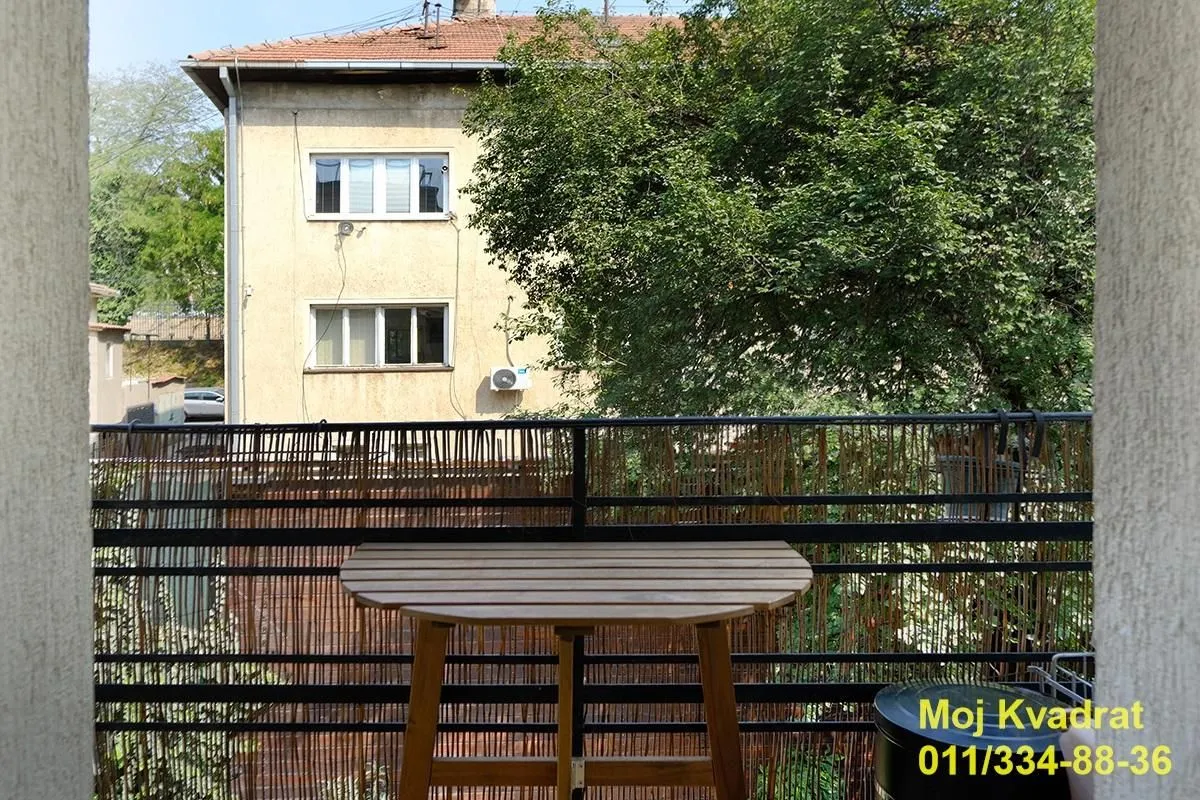 Pogled sa terase na susednu zgradu i drveće.