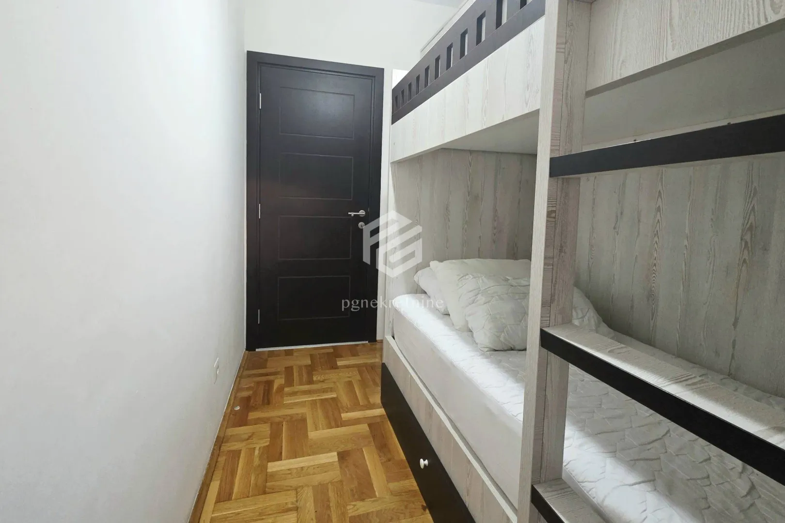Children's bedroom with a bunk bed and parquet flooring.