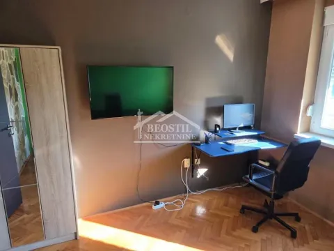 Radni kutak sa stolom, računarom i televizorom na zidu. - image 4