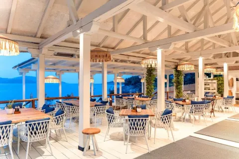 Natkrivena terasa restorana sa drvenim stolovima i pogledom na more. - image 14