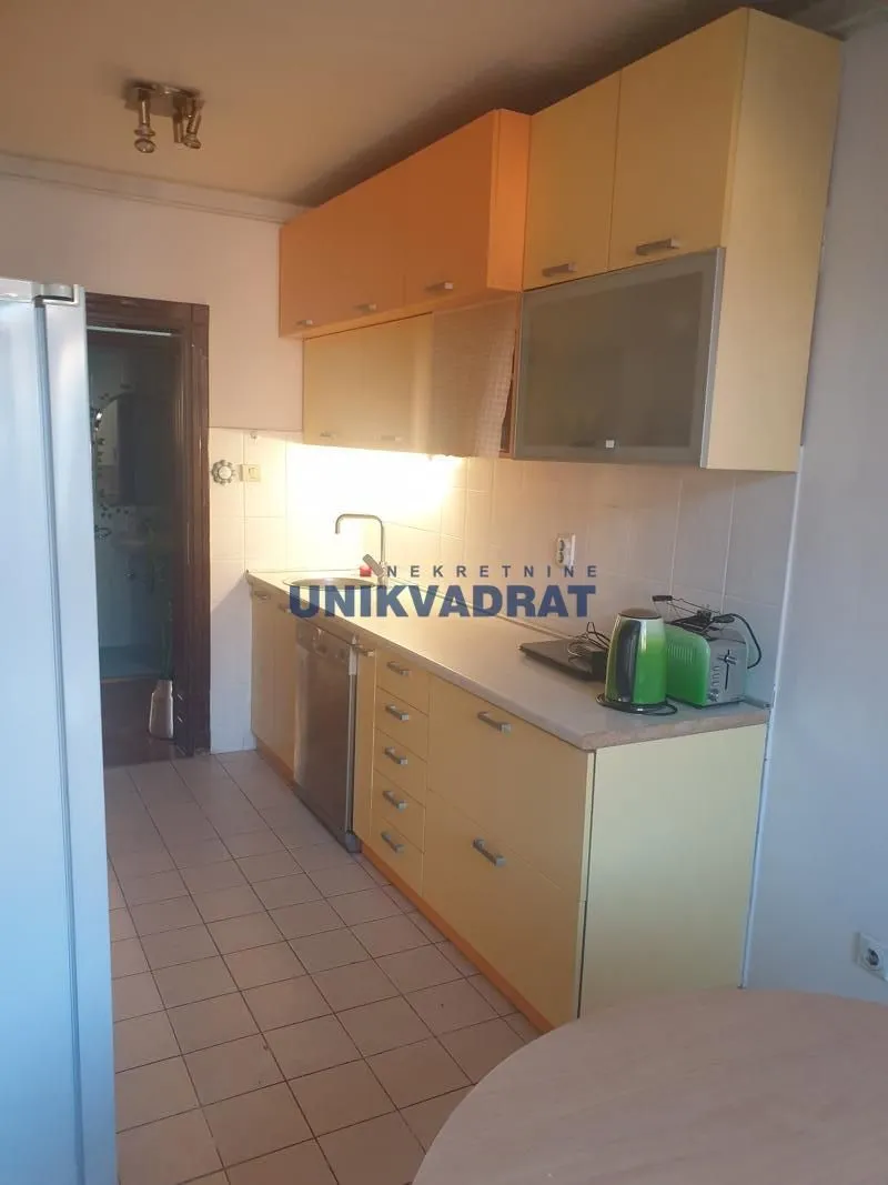 Manja kuhinja sa drvenim elementima i pločicama na podu.
