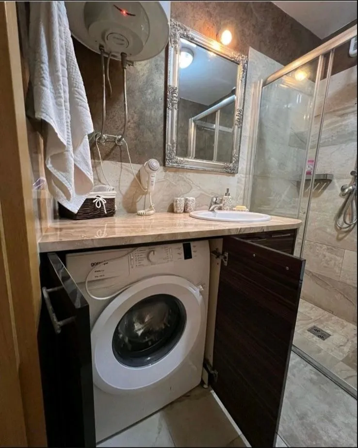 Manje kupatilo sa umivaonikom, tuš kabinom i veš mašinom.