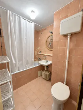 Kupatilo obloženo narandžastim pločicama sa kadom, umivaonikom i toaletom. - image 12