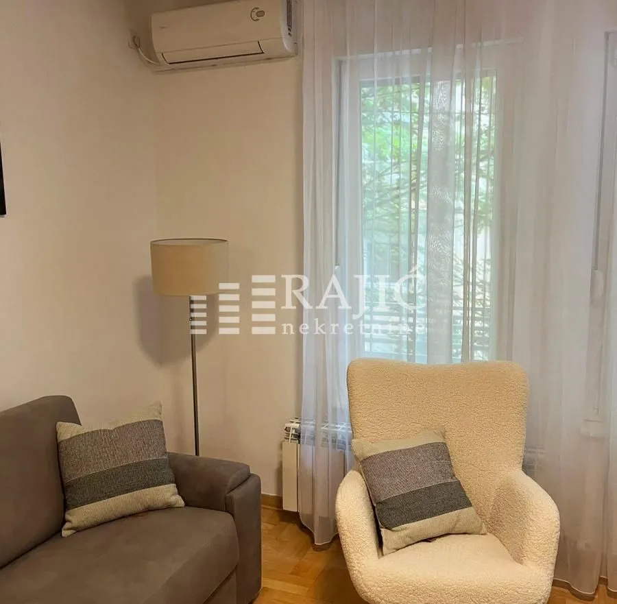 Living room with sofa, armchair and air conditioning unit.