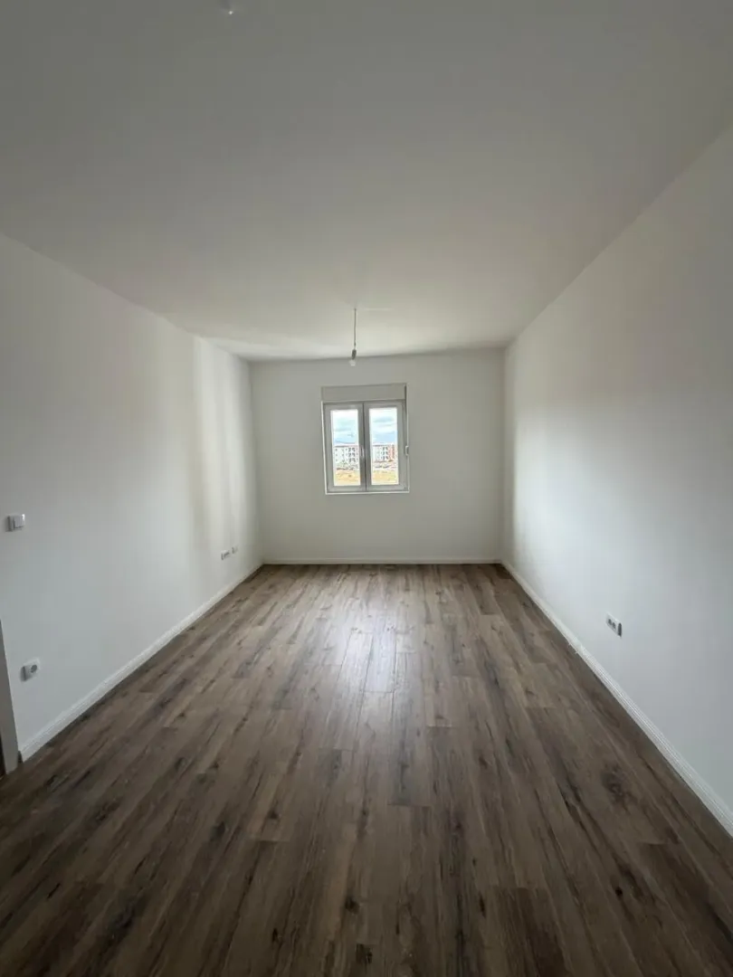 Empty room with white walls and wooden flooring.