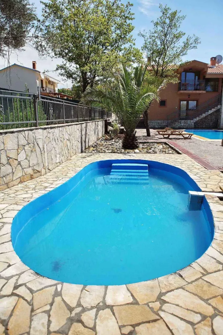 Dvorište sa bazenom okruženo kamenim popločanjem.