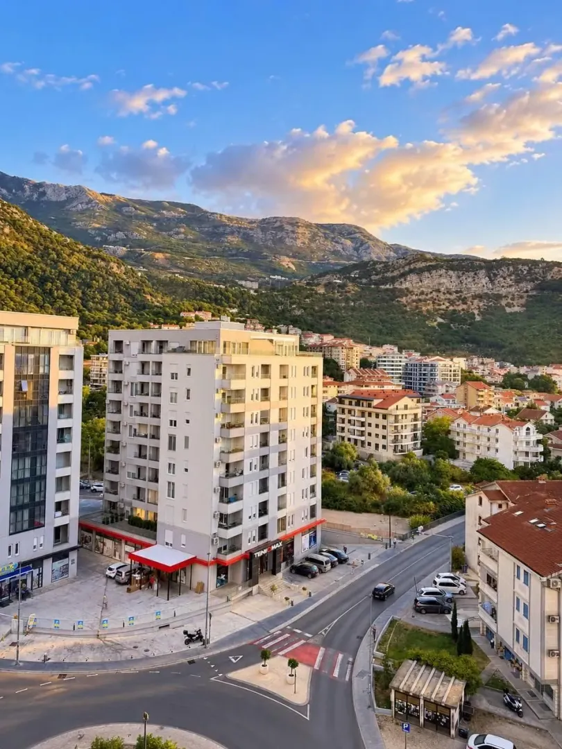 View from the terrace overlooking city buildings and mountains.