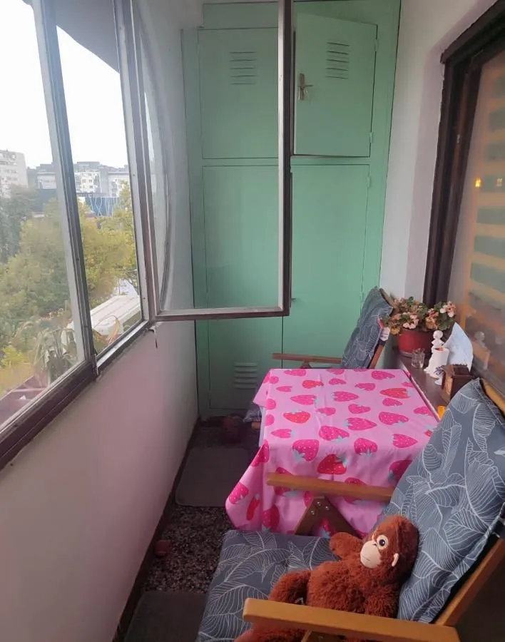 Zastakljeni balkon sa stolom, stolicama i ugradnim ormarom.