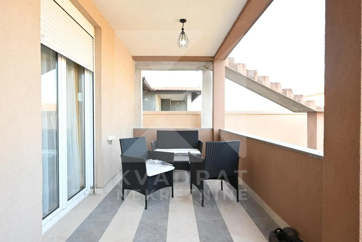Covered balcony with outdoor seating furniture and a table.