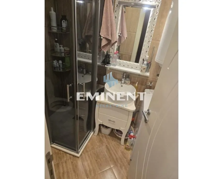 Smaller bathroom with a shower cabin, washbasin, and mirror.