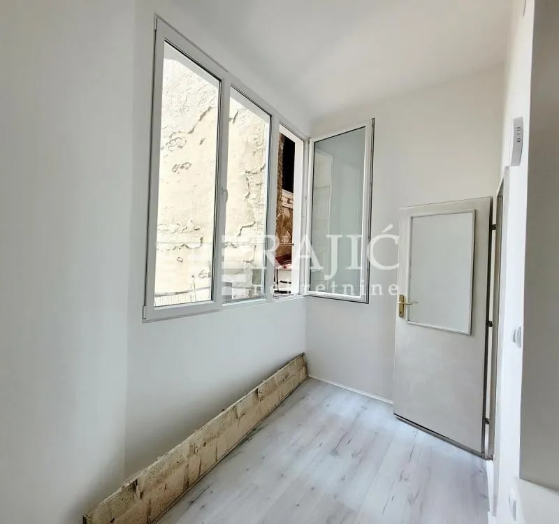 Bright enclosed terrace with white walls and laminate flooring.