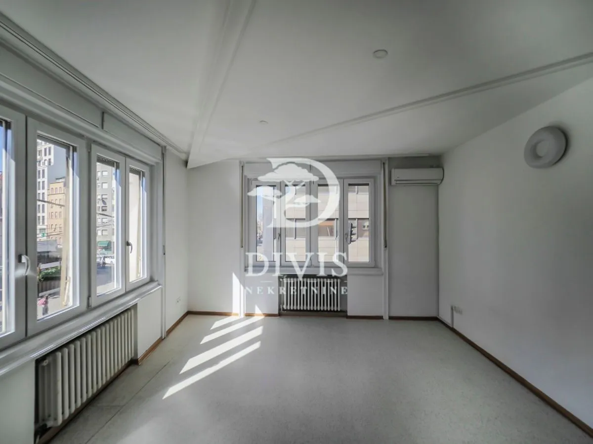 Empty bright room with white walls and large windows.