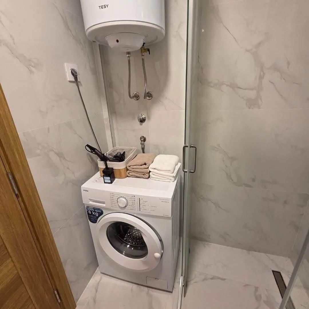 Bathroom with a washing machine and boiler.
