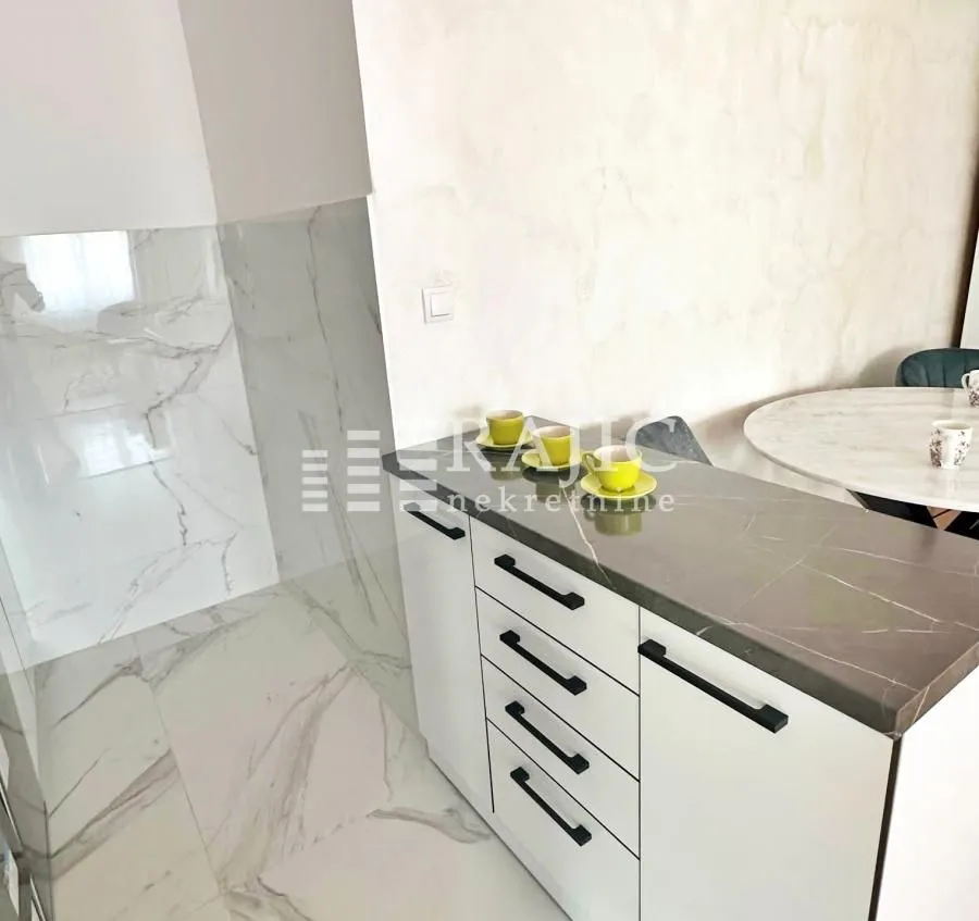 Modern kitchen with white cabinets and marble tiles.