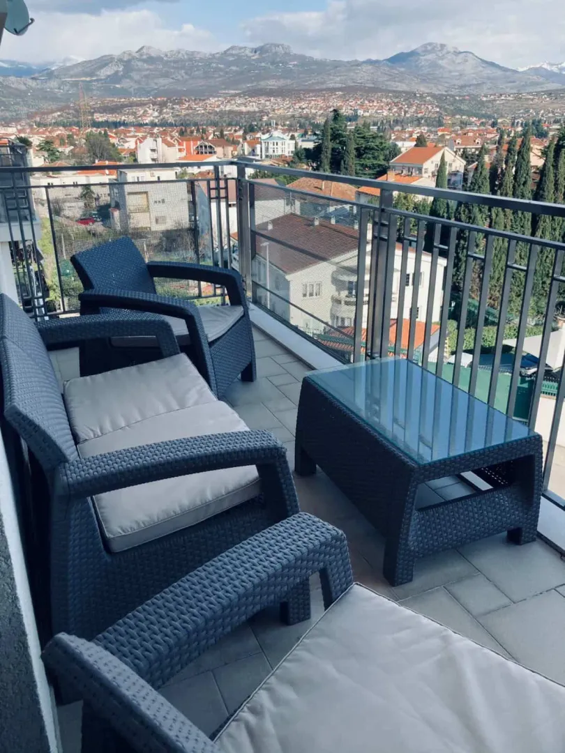 Namještena terasa sa garniturom za sjedenje i pogledom na grad i planine.
