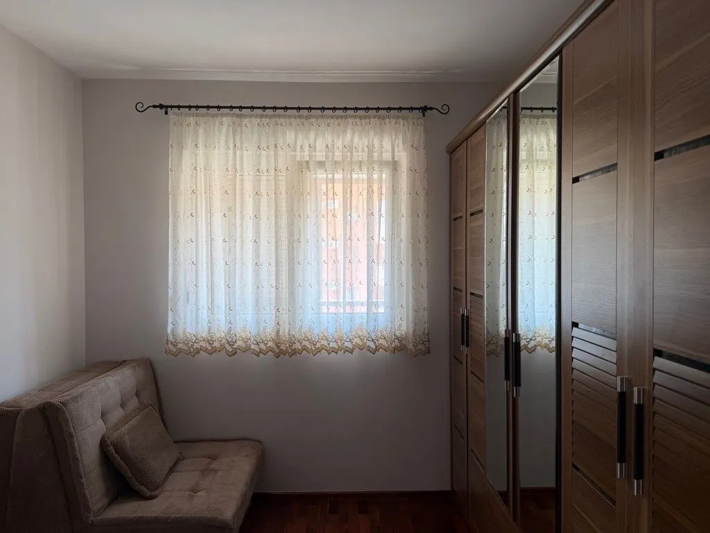 Small bedroom with a sofa bed, a window, and a large wooden wardrobe with a mirror.