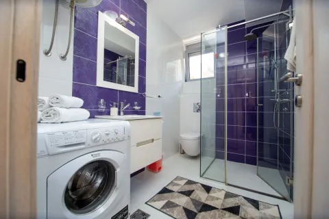 Modern bathroom with a walk-in shower, washbasin, and washing machine. - image 7