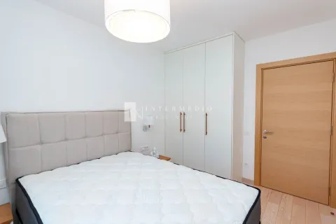 Svjetla spavaća soba sa bračnim krevetom, bijelim garderoberom i drvenim vratima. - image 10