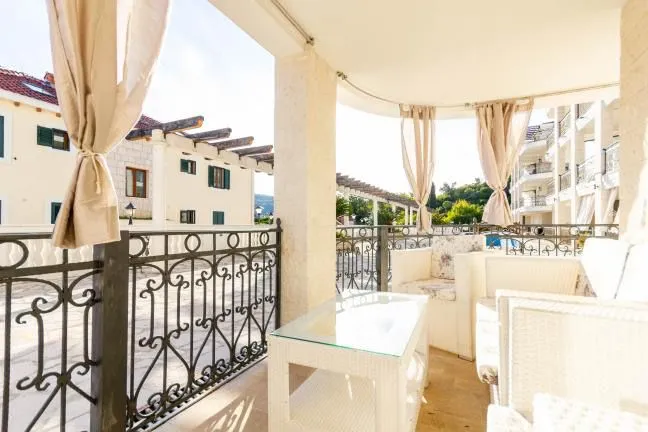 Spacious covered terrace with seating furniture and a view of surrounding buildings.