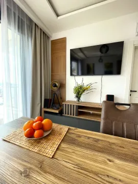 View of the living room with a wooden table and a wall-mounted TV. - image 2