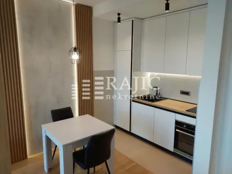 Modern kitchen with white units and a dining table. - image 3