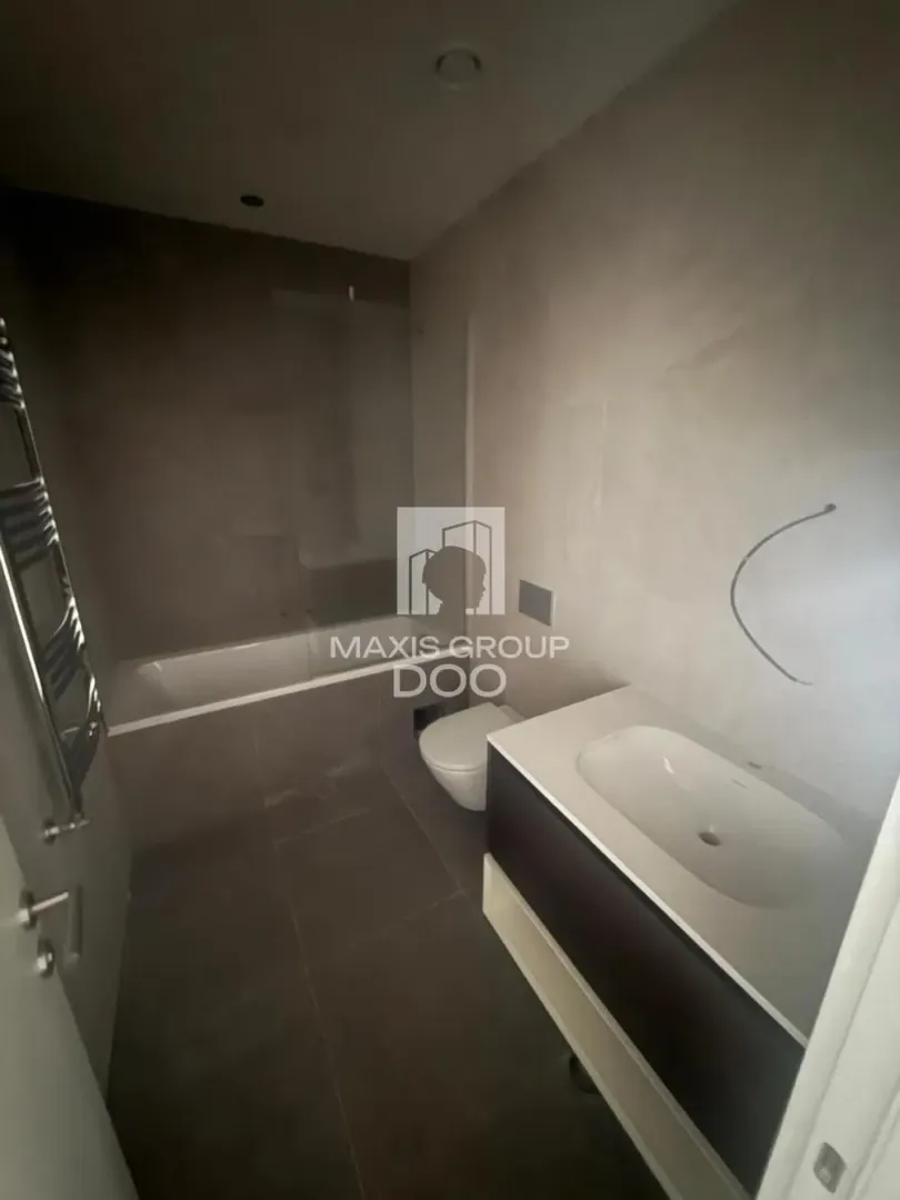 Modern bathroom equipped with a shower, washbasin, and sanitary fixtures in dark tones.