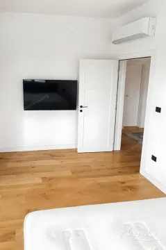 View of the bedroom with wooden flooring, a wall-mounted TV, and an air conditioning unit. - image 5