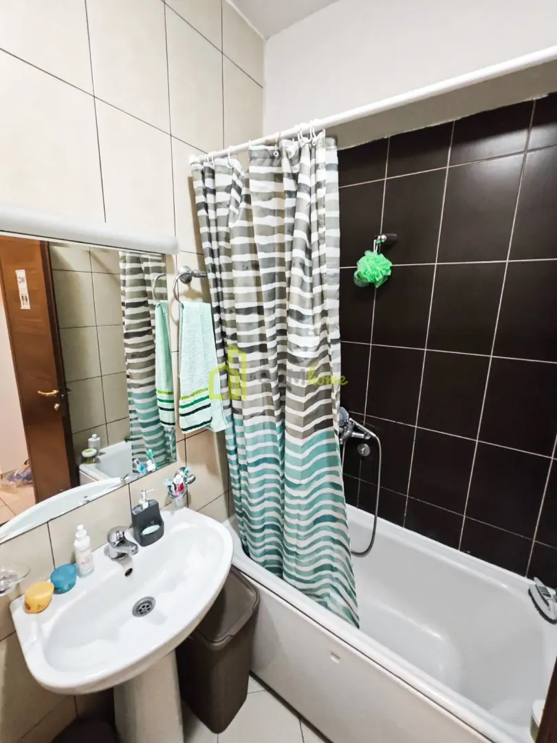 Bathroom with a sink, mirror, and bathtub with a curtain.