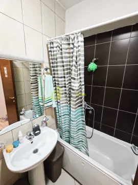 Bathroom with a sink, mirror, and bathtub with a curtain. - image 9
