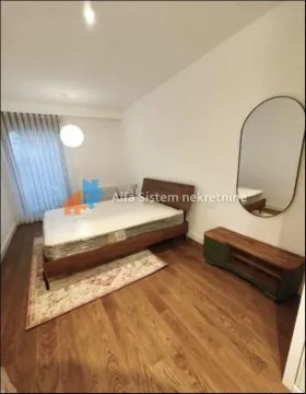A bedroom with a double bed, wooden dresser, and a wall mirror. - image 11