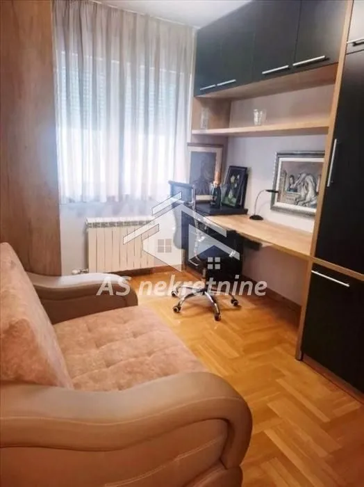 Dnevna soba sa radnim stolom, kaučem i drvenim podom.