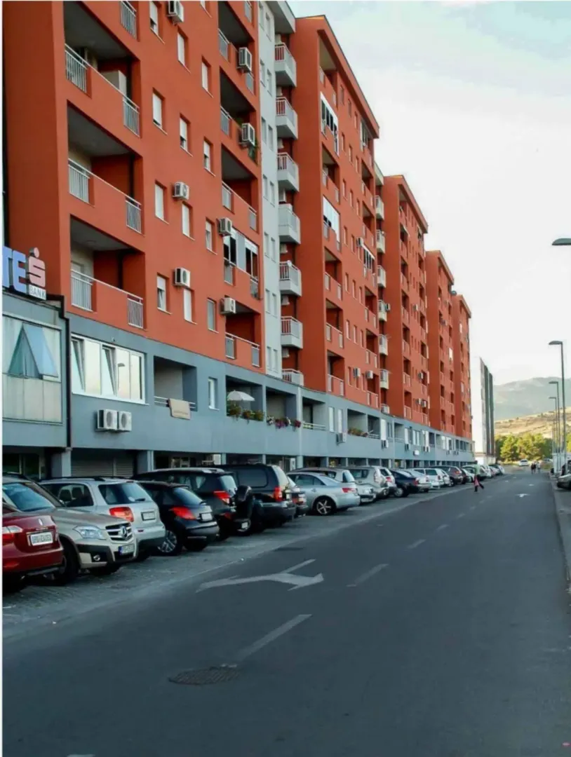 Exterior view of a modern multi-story residential building with parking.