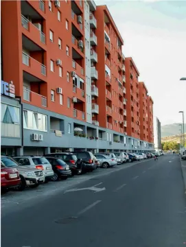 Exterior view of a modern multi-story residential building with parking. - image 8
