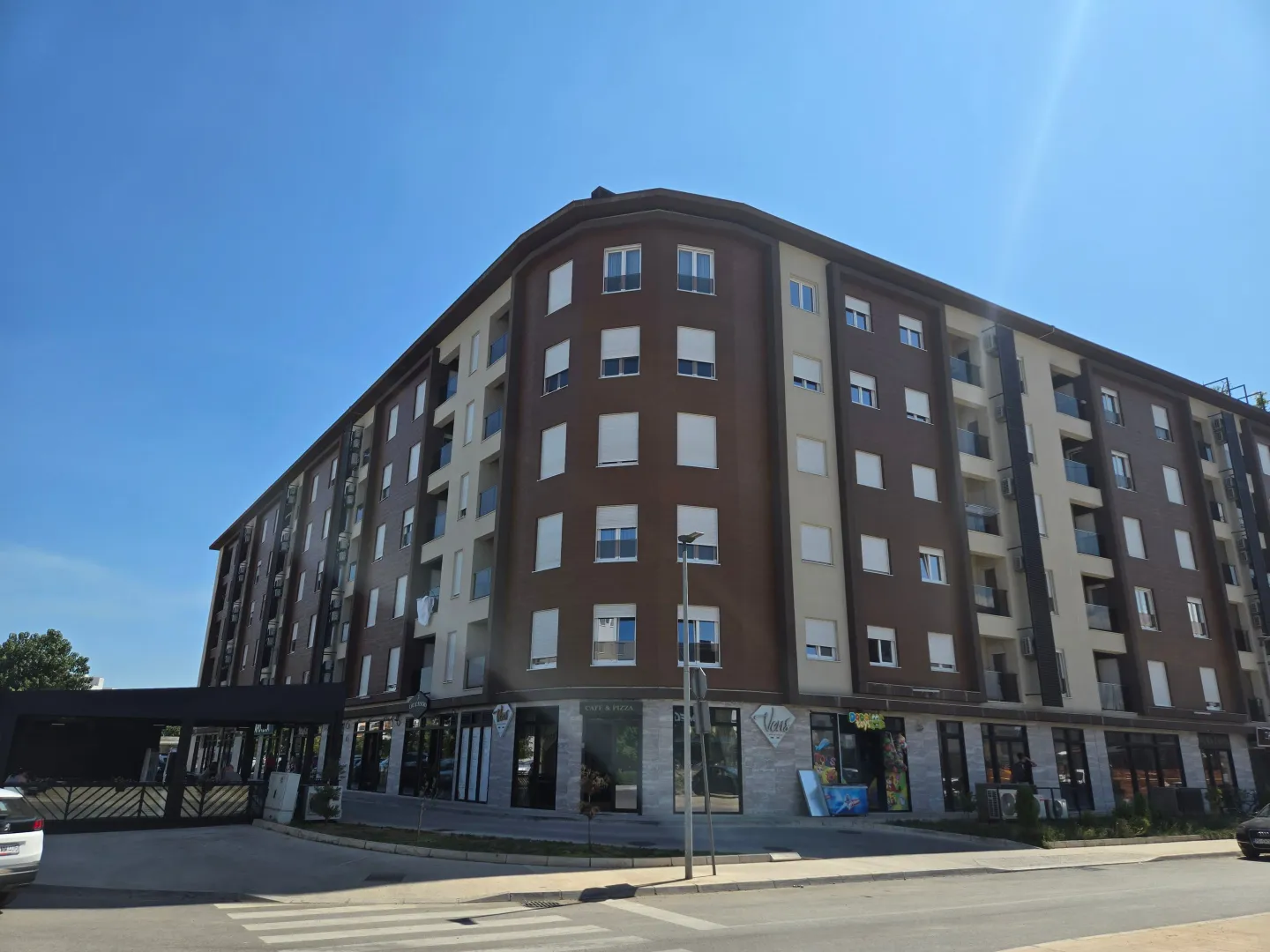 Exterior view of a multi-story residential and commercial building with a sidewalk and street in the foreground.