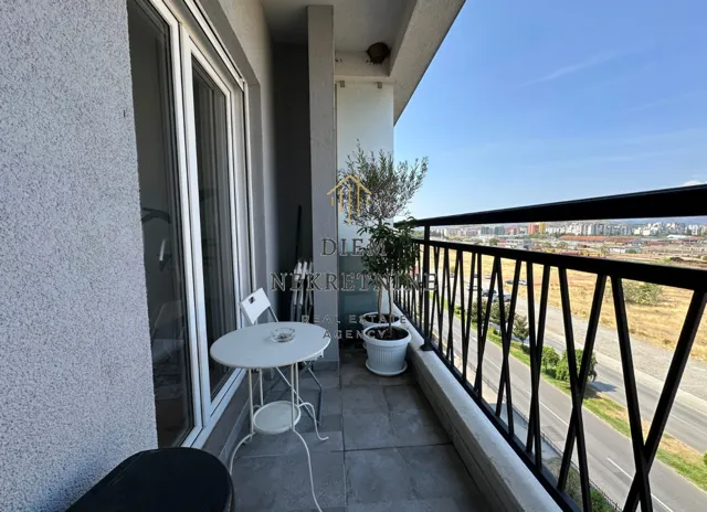 Manji namješten balkon sa stolom, stolicama i saksijama sa biljkama.