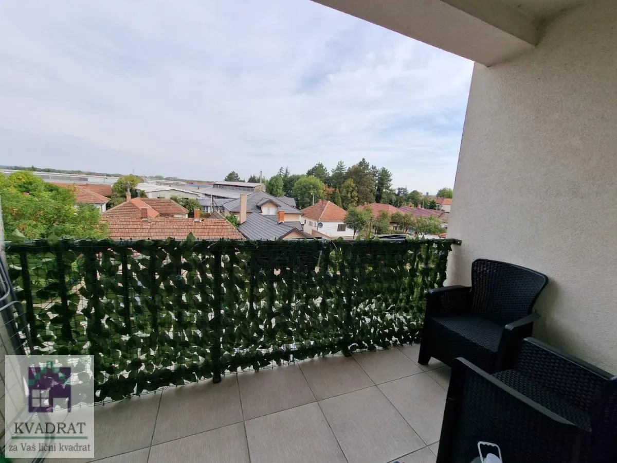 Natkriveni balkon sa garniturom za sedenje i pogledom na naselje.
