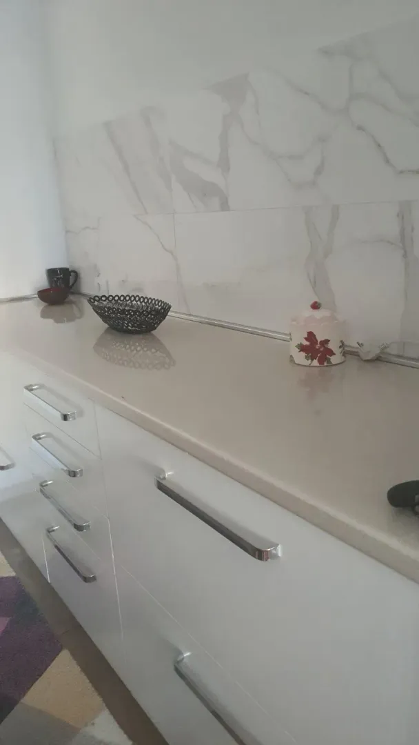 Kitchen cabinets with a light countertop and decorative backsplash tiles.