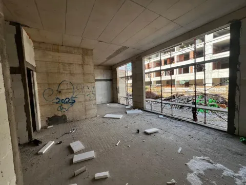 Unfinished room in grey phase under construction with large windows and a view of the construction site. - image 7